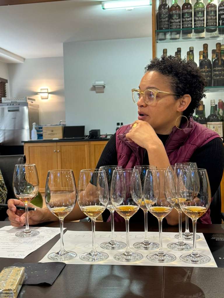 Jamaica at a Madeira tasting with a full row of wine glasses in front of her